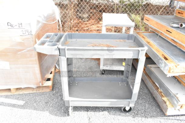 2 gray poly 3-tier carts on commercial casters, sturdy design, ideal for industrial use, weathered condition.