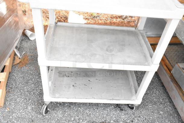 Two gray poly 3-tier carts on commercial casters; used condition, sturdy design for versatile utility.