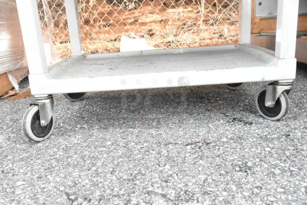 Two gray poly 3-tier carts with commercial casters on asphalt. Sturdy, mobile design ideal for various uses.