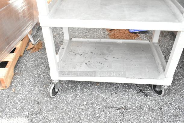 Two gray, three-tier poly carts on commercial casters, showing wear, ideal for storage and transport.