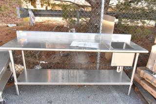 Stainless steel table with sink bay, backsplash, and under shelf. Features a clean surface and sturdy frame for durability.
