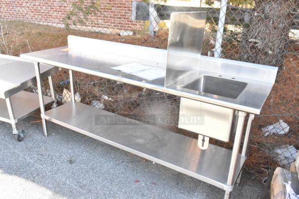 Stainless steel table with sink bay, backsplash, and under shelf. Features durable construction and spacious design, ideal for kitchens.