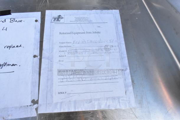 Stainless steel table with sink bay, backsplash, and under shelf. Includes project return paperwork, indicating a replacement.