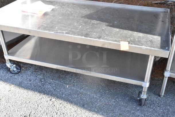 Stainless steel equipment stand with under shelf, on commercial casters. Durable, with light wear, ideal for kitchen use.