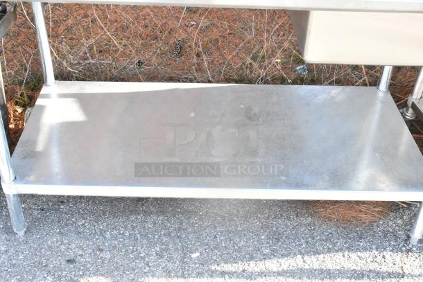 Stainless steel table with sink bay, backsplash, undershelf; good condition, ideal for kitchen use, sturdy construction.