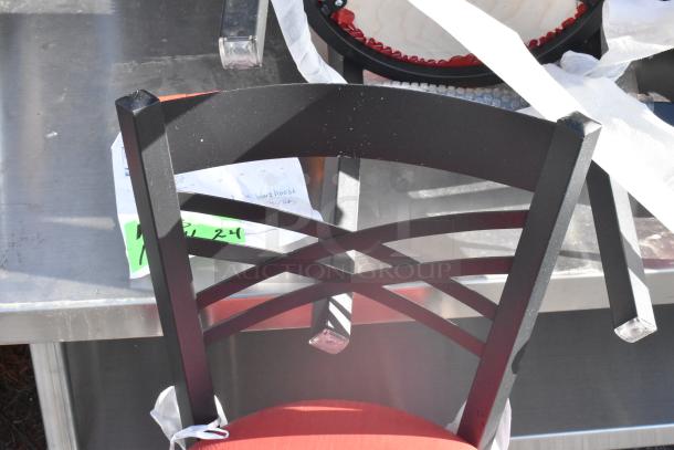 Black metal cross back chair with red seat cushion, dining height. Shows paperwork and green tag, indicating auction details.