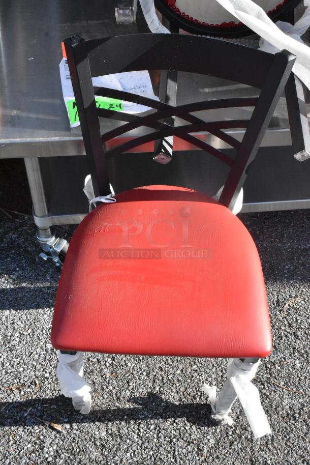 Black metal dining chair with cross back and red seat cushion. Features protective wrapping on legs. Good condition.