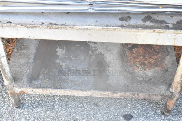 Rusted metal table with under shelf, visible wear and corrosion. Suitable for restoration or industrial use.