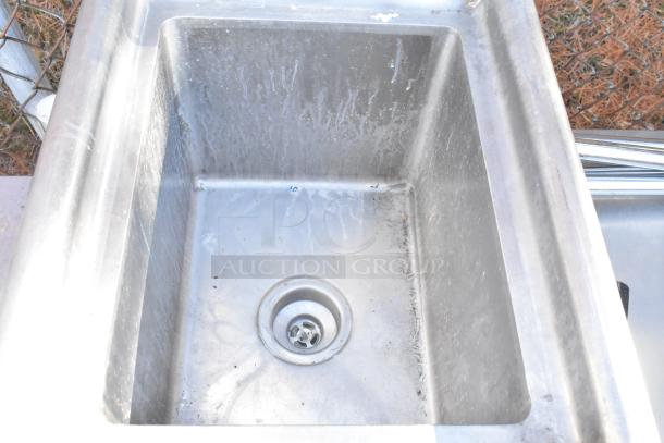 Stainless steel single bay sink with visible wear, showing drain and basin details. Ideal for kitchen or utility use.