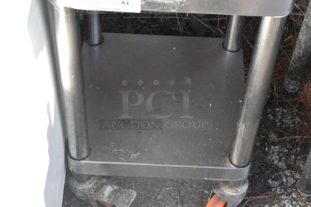 Stainless steel rice cooker stand with under shelf, on commercial casters. Shows moderate wear, ideal for kitchen equipment.