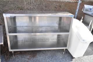 Stainless steel table with two under shelves, showing some wear. Includes tags indicating lot number and previous use.