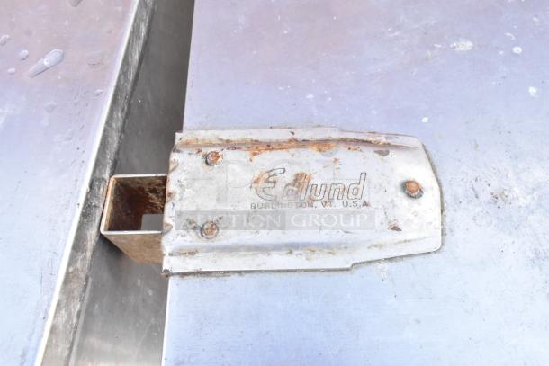 Stainless steel table with metal under shelf and Edlund can opener mount. Signs of wear and rust on mount.