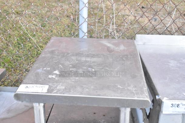 Stainless steel table with metal under shelf, shows wear, auction tag "309" visible, sturdy construction.