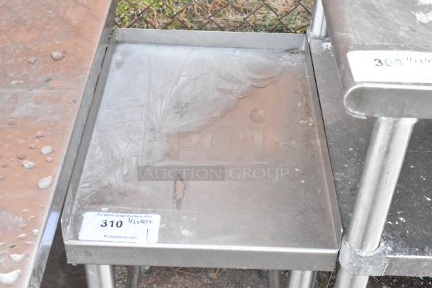 Stainless steel table with visible label "310." The table shows signs of wear and rust, sturdy metal legs.