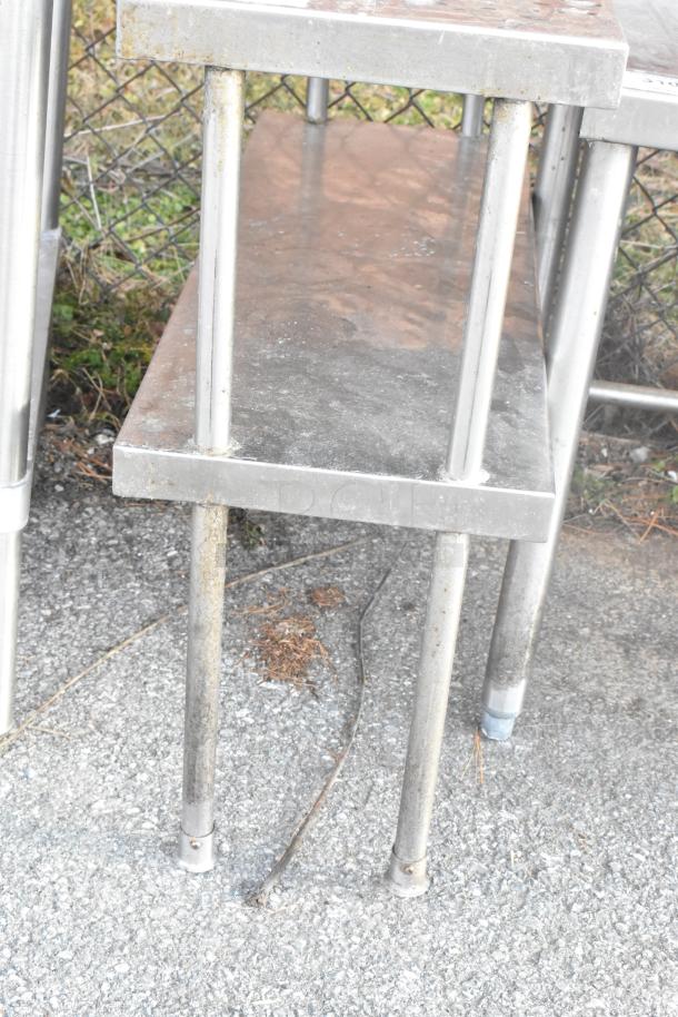 Stainless steel 2-tier over shelf with visible scratches and signs of wear. Functional for kitchen or storage use.