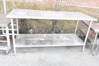 Stainless steel table with metal under shelf, outdoor setting. Used condition, visible surface marks. Perfect for commercial use.