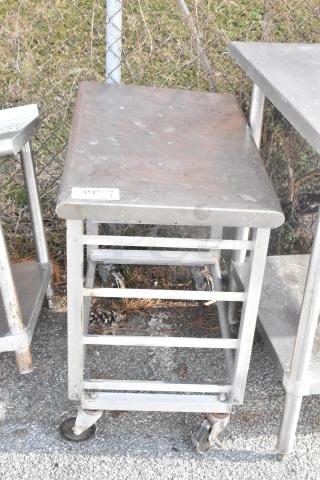 Metal pan rack on commercial casters, sturdy metal frame with multiple slots, some surface rust and wear visible. Tag reads "$13 8/26 312V".