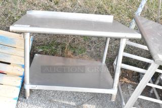 Stainless steel table with metal under shelf, used condition. Features a solid work surface and sturdy construction. Perfect for industrial settings.