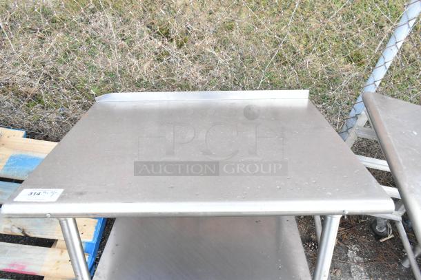 Stainless steel table with metal under shelf, shown outdoors. Solid construction and clean surface. Tag indicates "314 1/2".