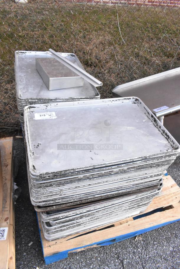 Stack of 102 metal full-size baking pans on wooden pallets. Visible wear; labels indicate auction item number 315.