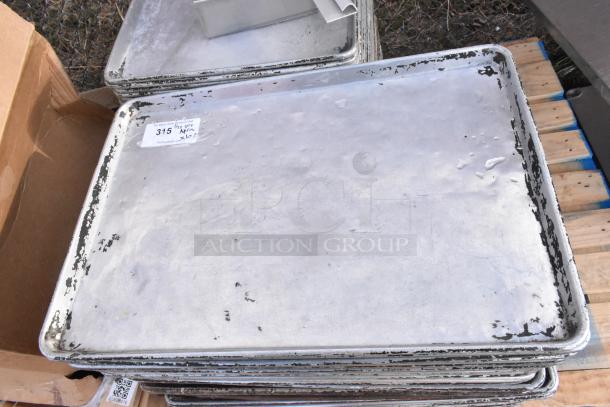 Stack of 102 metal full-size baking pans, used condition, visible label indicating auction lot "315, Qty 102."