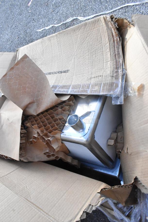 Three new scratch and dent outdoor table base columns with spider bar, model 427TBCLRD337, partially unpacked.