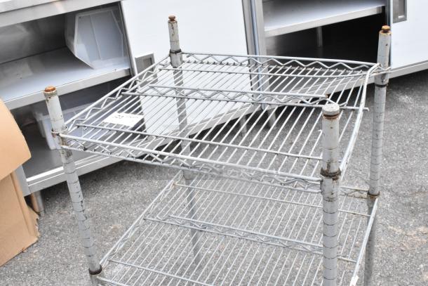 Chrome finish 2-tier wire shelving unit with visible rust on poles. Used condition, ideal for storage needs.