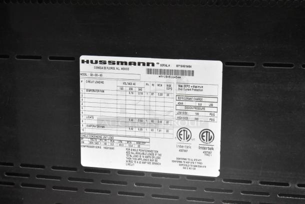 Hussmann Q3-SS-6S merchandiser tag showing model info, electrical specs, refrigerant charge, and compliance labels.