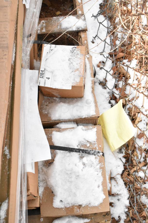 Boxes of scratch and dent items, snow-covered, labeled "DB4", including Quantum and Metro shelving components.