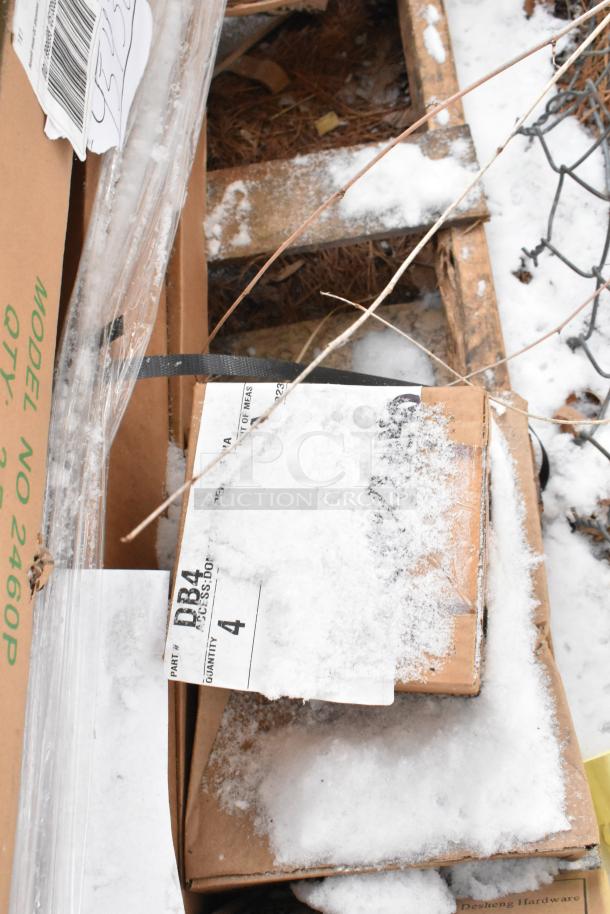 Cardboard boxes with tags labeled "DB4" and "2460P" partially covered in snow, containing scratch and dent food service items.