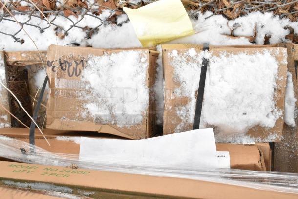 Cardboard boxes with snow cover, labeled model no 2460P, qty 2 pcs, strapped on a pallet outdoors.
