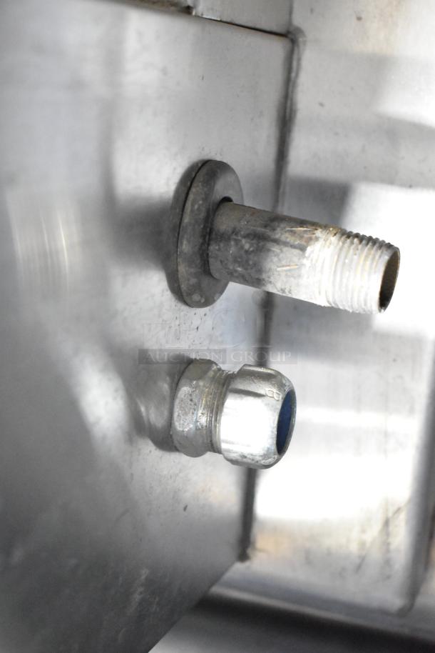 Close-up of the gas and water fittings on a brand new 2021 Groen TDH-48C stainless steel 12-gallon steam tilting kettle.