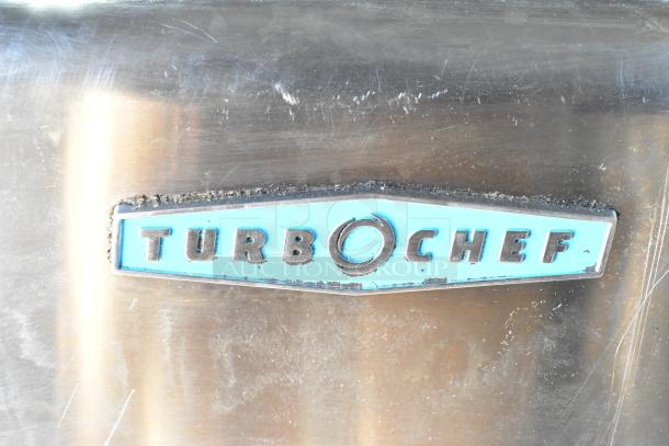 Turbochef HhC2020 badge on stainless steel surface of 2017 rapid cook conveyor oven, showing some wear.