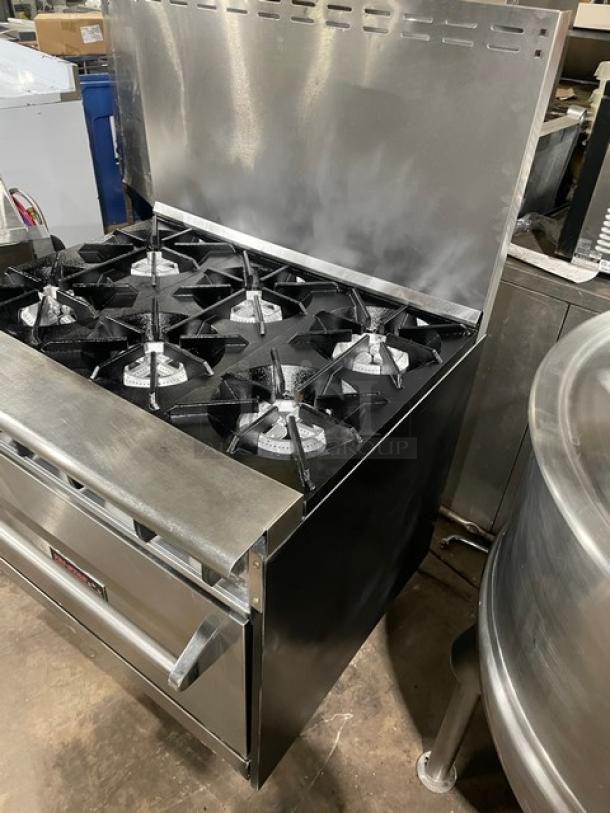 Tri-Star stainless steel gas-powered 6-burner range/oven combo with back splash and wired oven rack on legs.