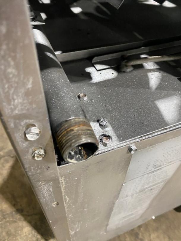 American Range stainless steel 4-burner gas range/oven combo, showing corner detail with attached pipe. Condition appears used.