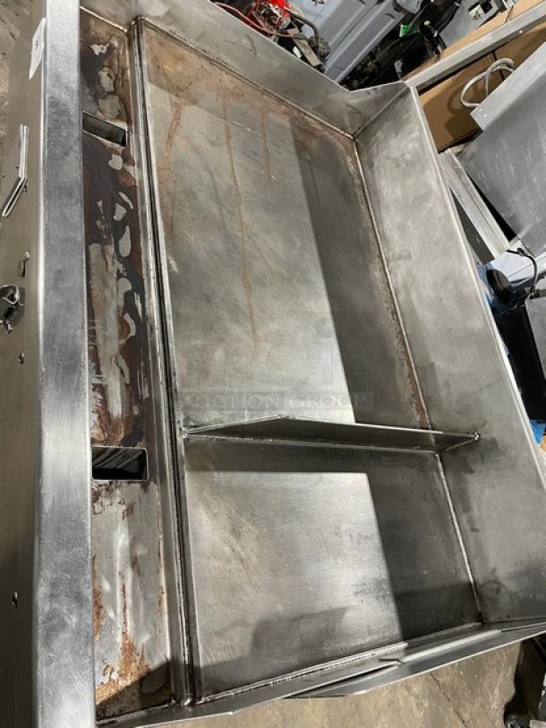 WoodStone stainless steel 48" gas plancha flat griddle, includes back and side splash, undershelf stand, and casters. Visible wear.