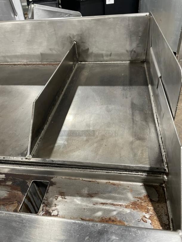 WoodStone commercial stainless steel gas-powered griddle, 48" countertop with back and side splash. Includes single undershelf stand on casters. Serial Number: GP1B16MAY1704992.