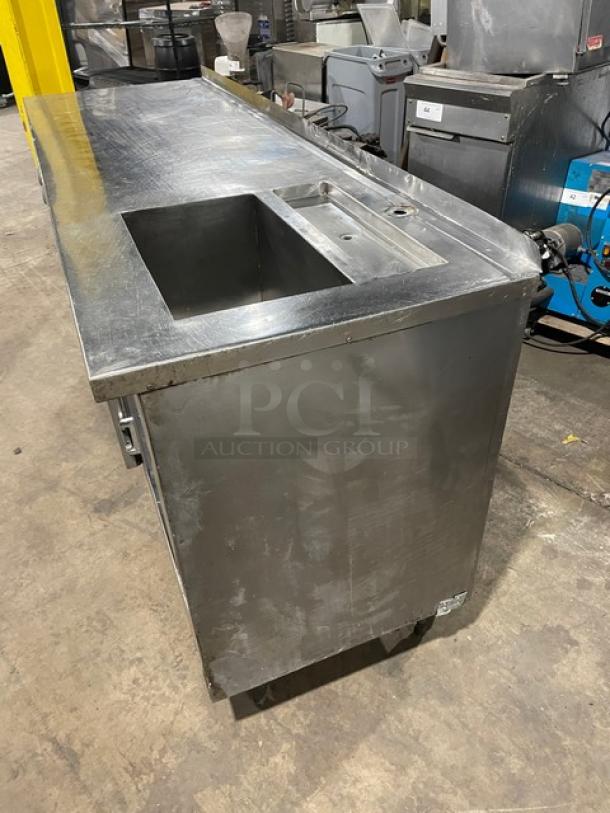 Commercial stainless steel 2-door refrigerated worktop station with single compartment sink on legs; visible wear.