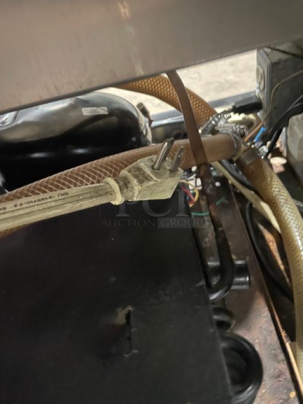 Commercial stainless steel 2-door refrigerated worktop station with single compartment sink, showing hoses and power connections.