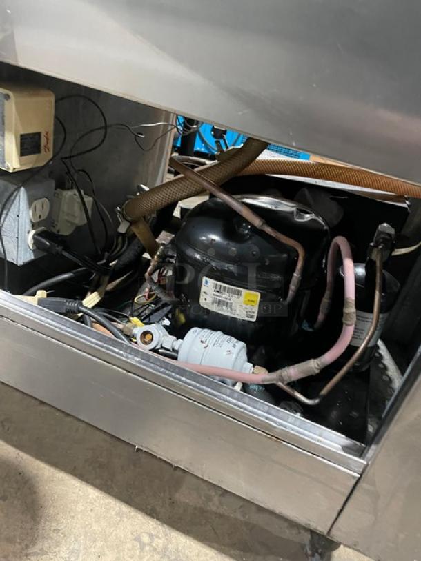 Commercial stainless steel refrigerated worktop with two doors and single compartment sink. Visible compressor and wiring.