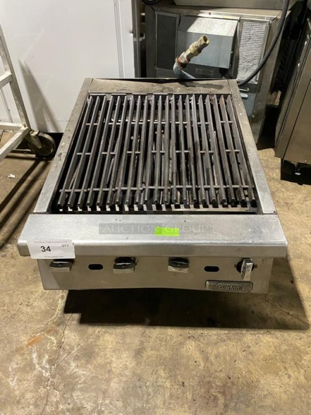 Garland Commercial 24" countertop char broiler with stainless steel body and cast iron grates. Gas-powered, on legs.