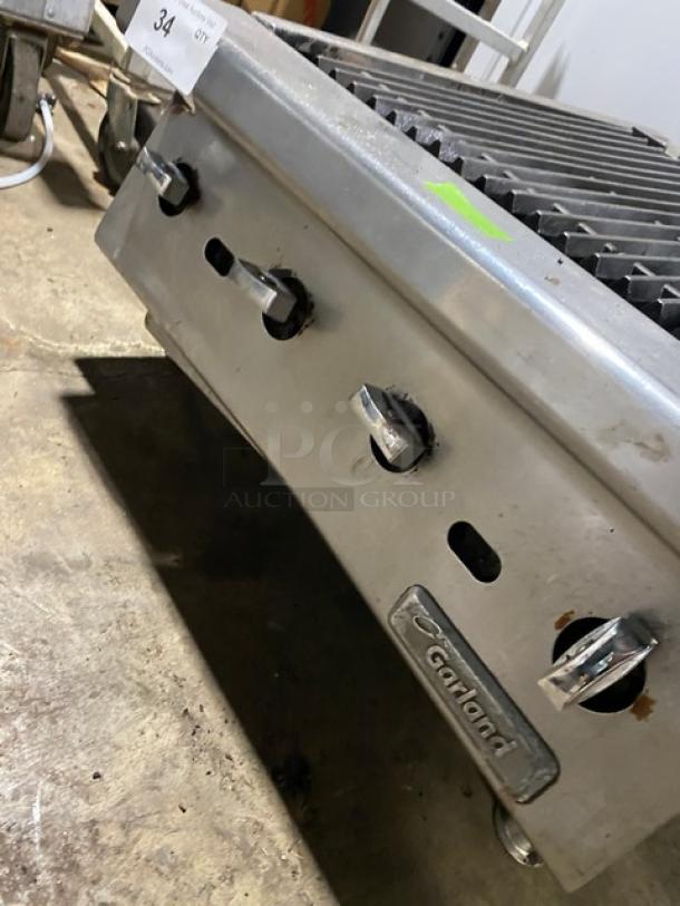 Garland 24" stainless steel gas char broiler with cast iron grates, visible brand label, mounted on legs, in working condition.