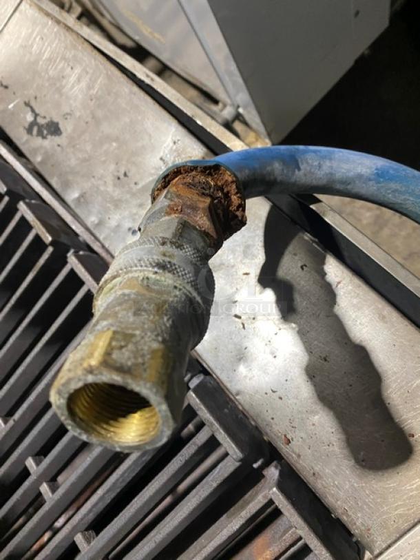 Garland stainless steel 24" gas char broiler with cast iron grates, blue gas hose, and rusted connector. Working condition.