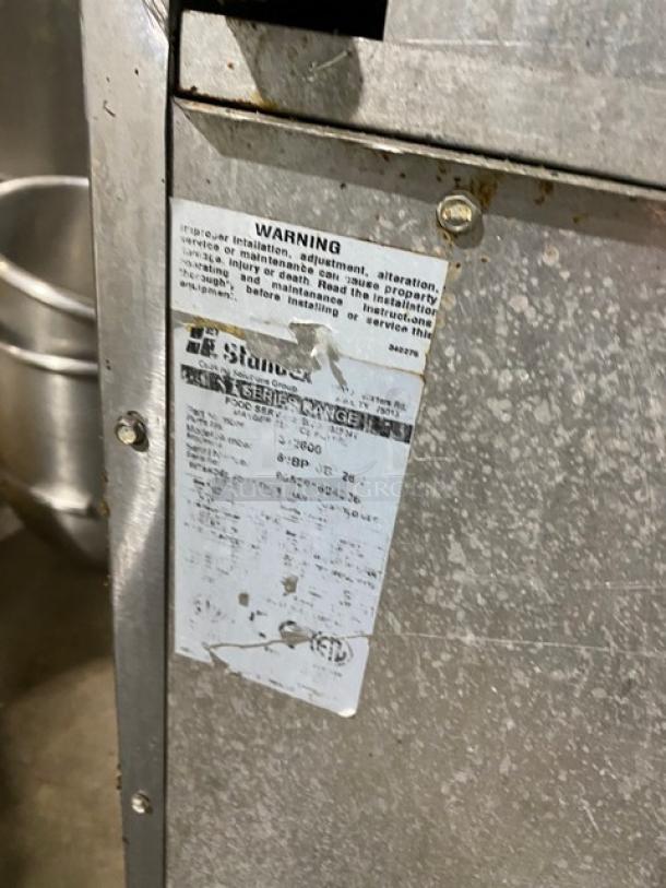 Bakers Pride stainless steel 10-burner range with double oven, backsplash, salamander shelf, and casters. Visible wear on label.