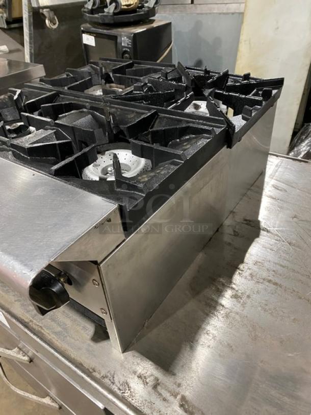 American Range stainless steel 4-burner gas countertop range, commercial-grade, shows some use. Visible controls on the side.