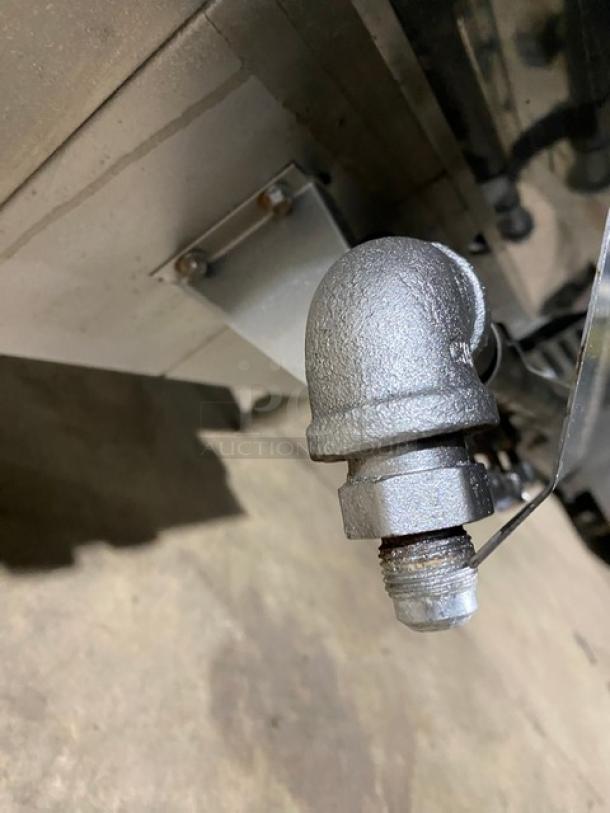 Commercial stainless steel gas-powered Chinese smoker oven. Close-up of pipe fitting. Smoker on legs.