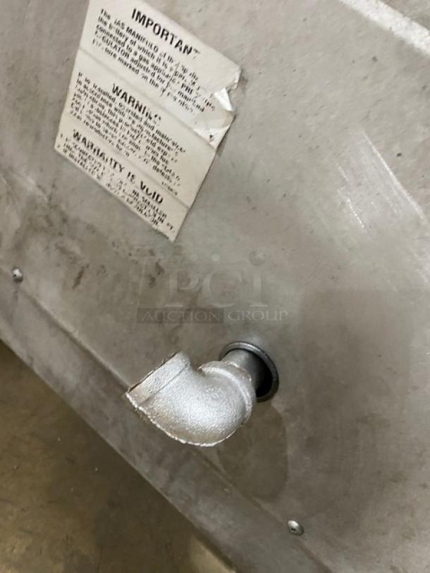 Southbend stainless steel gas-powered upright double deck broiler's back view. Visible warning label, mounted on casters.