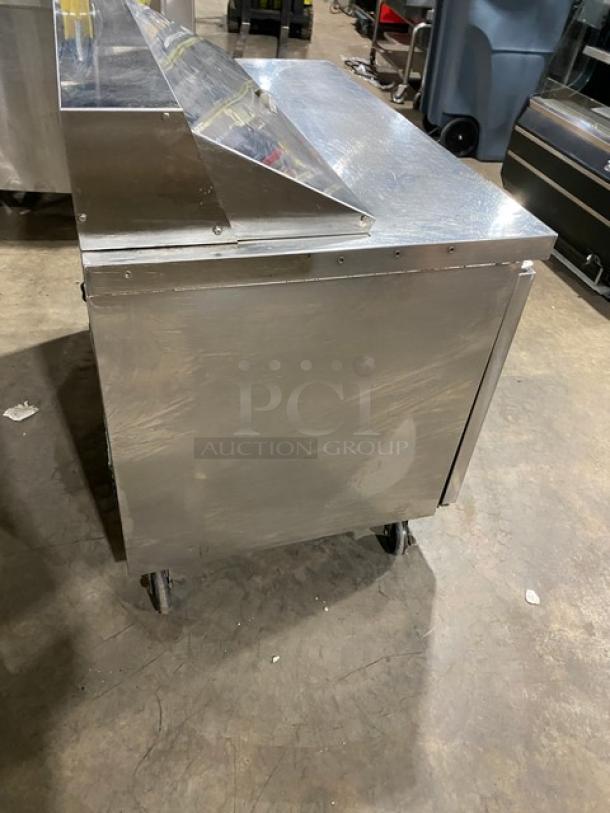 Dukers DSP48 stainless steel salad prep table, bain marie style, with wired rack, on casters, in used condition.