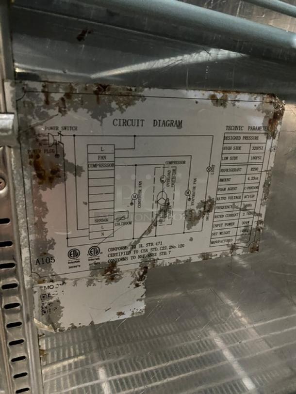 Universal commercial stainless steel reach-in freezer with visible circuit diagram label, showing signs of wear.