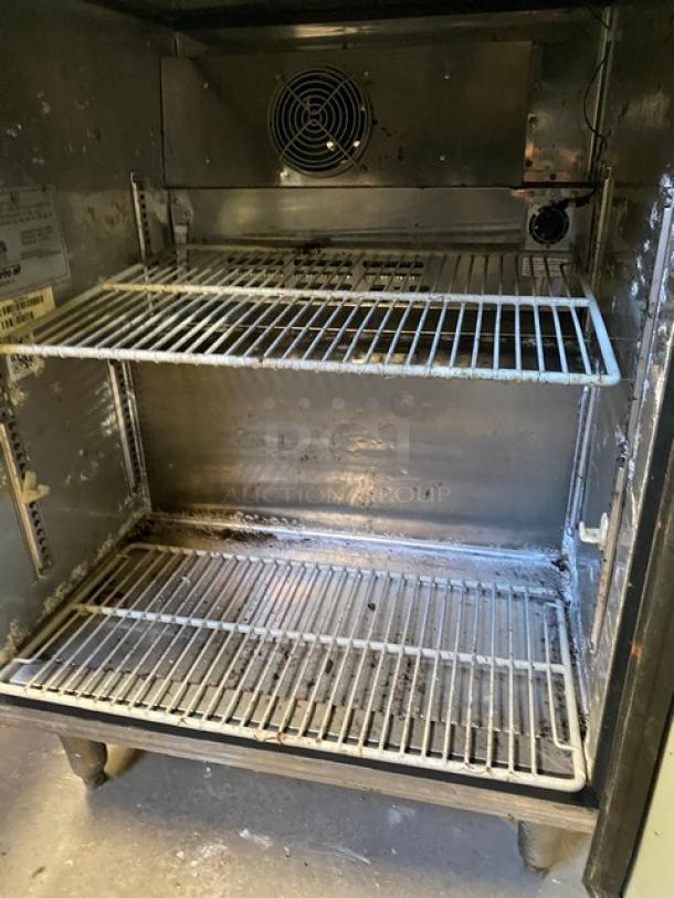 Delfield stainless steel undercounter refrigerator, model 406CA-DHL-DD1, with coated wired rack, on casters, interior view.